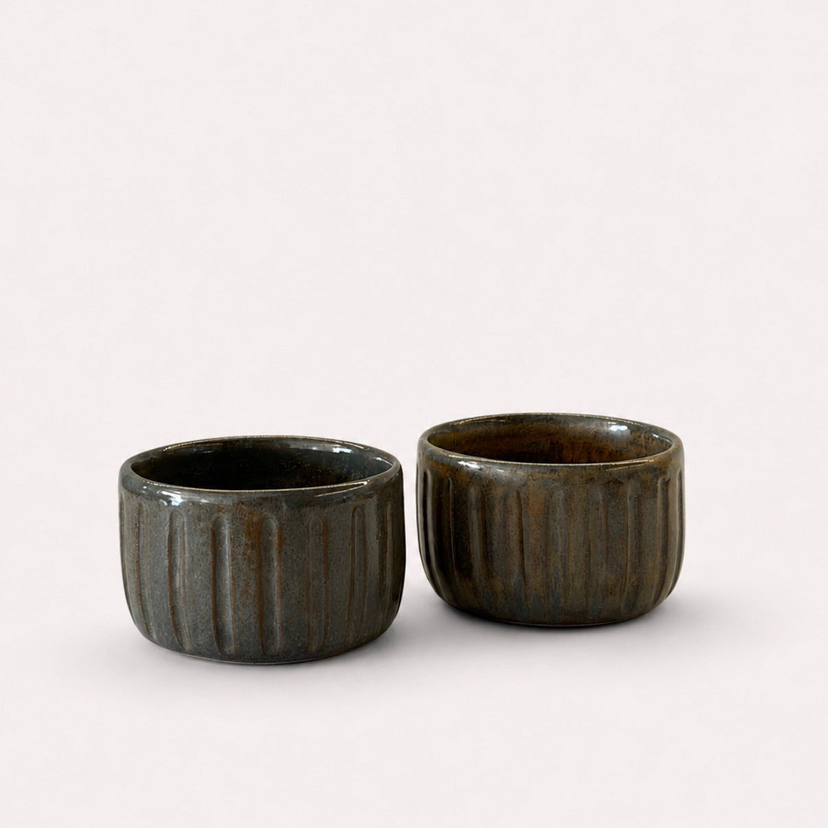 Two small dark brown ribbed ceramic cups with a glossy finish.