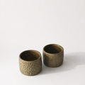 Two small textured ceramic cups with a metallic bronze/green finish.